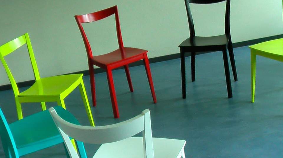 Ein Stuhlkreis mit bunten Stühlen in blau, grün, rot und gelb