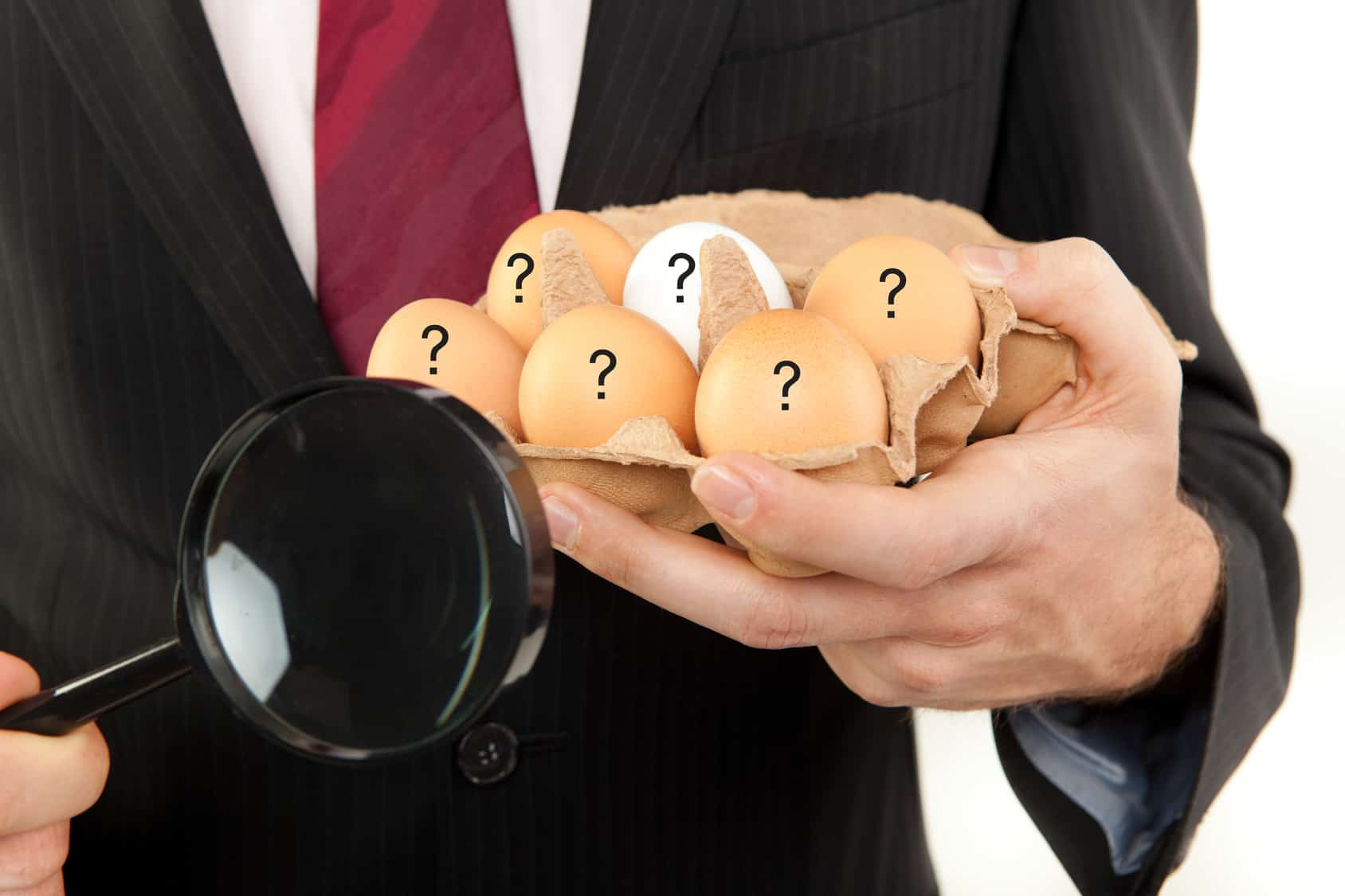 Mann im hält links eine Packung Eier mit Fragezeichen und rechts eine Lupe hoch