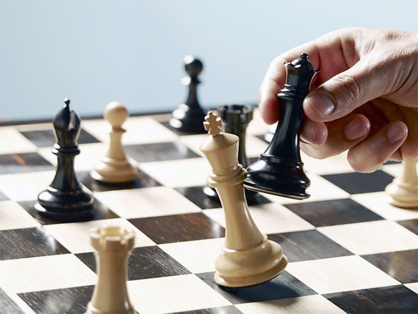 Tabuleiro de xadrez com peças de xadrez em que uma peça preta captura a rainha.