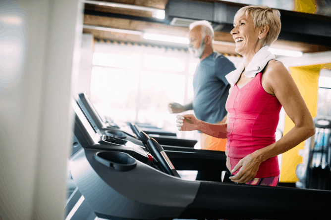 An elderly lady and an elderly gentleman keep fit doing cardio