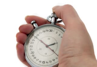 One hand holds an old analogue stopwatch. The stopper is set at 25s