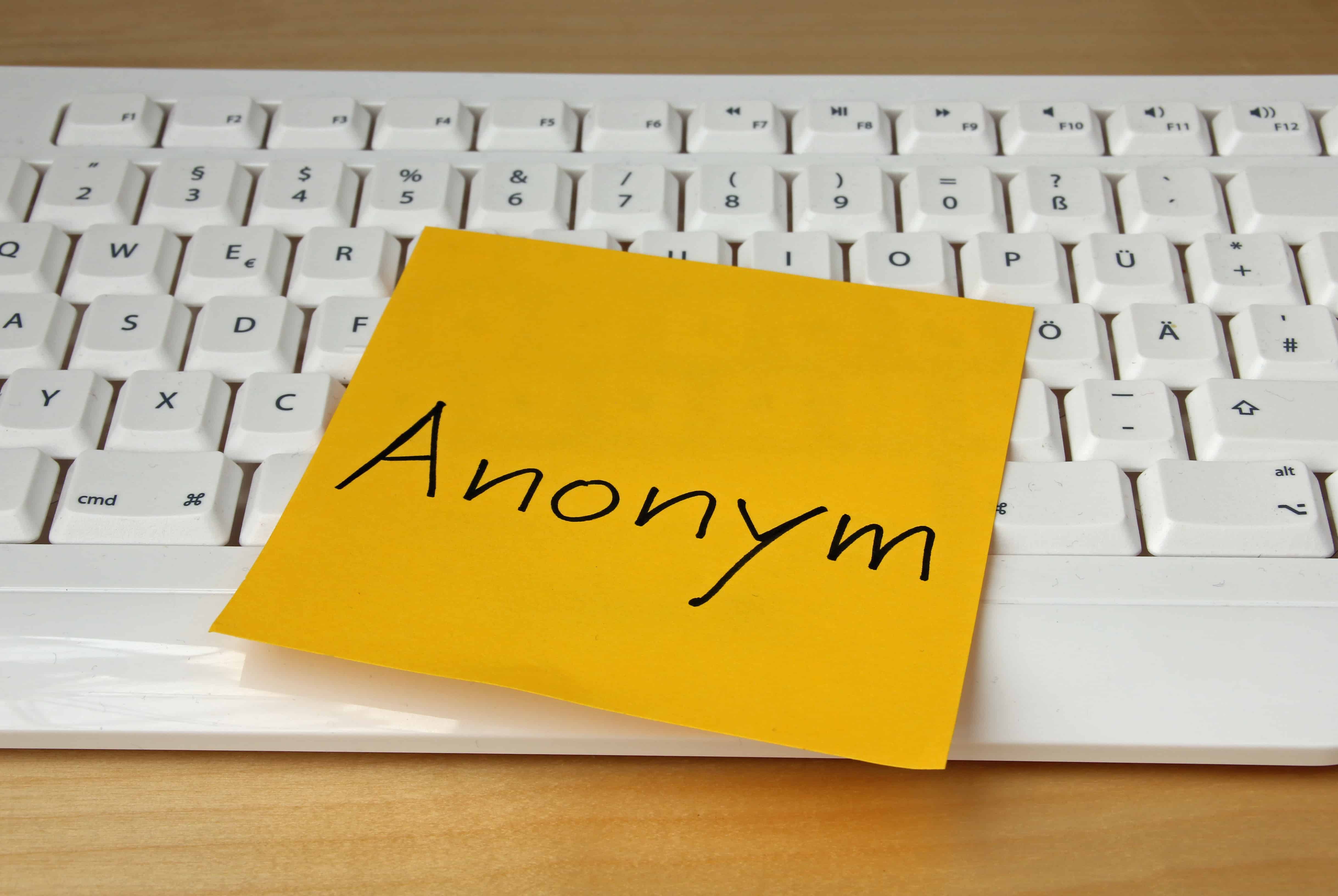 Eine weiße Tastatur mit einem orangenem Klebezettel darauf: Anonym