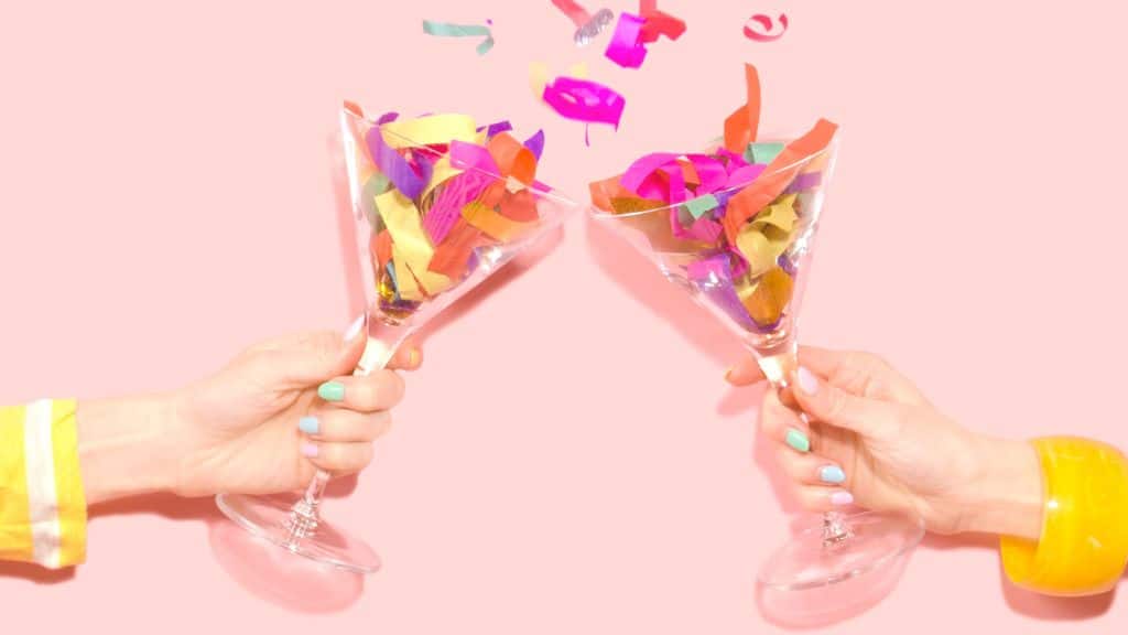 Two champagne glasses toasting with confetti