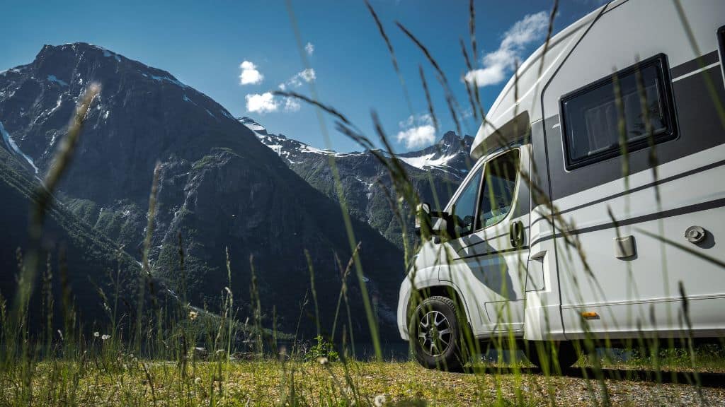 Ein Camper, der auf einer Wiese steht mit Blick auf die Berge.